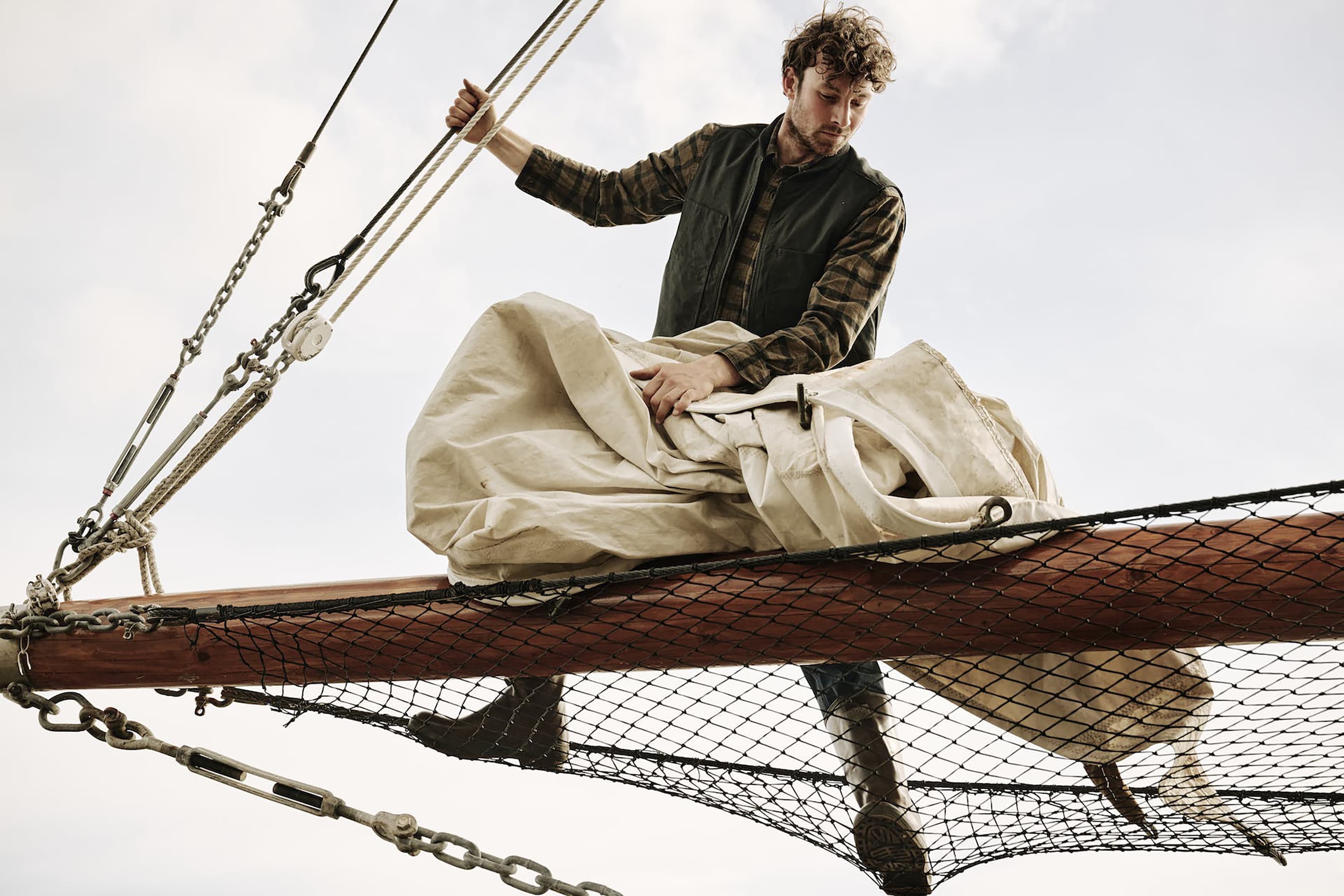 A sailor working the sails on a ship.